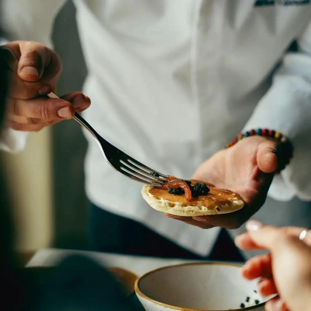 Chef presenting an elegant caviar blini, fine dining plating